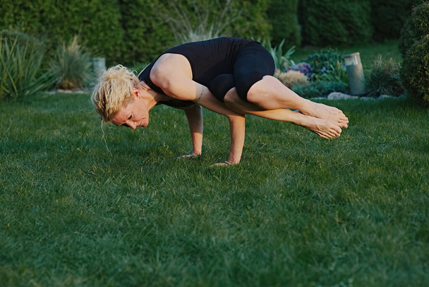Young woman doing yoga in meditation posture on a mat in the garden. - Foto, afbeelding