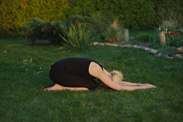 Young woman doing yoga in meditation posture on a mat in the garden. - Valokuva, kuva