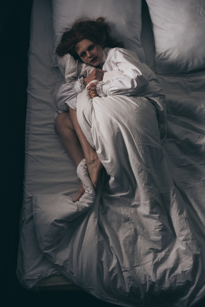 Gecelikli paranormal kız yatakta yatıyor. - Fotoğraf, Görsel