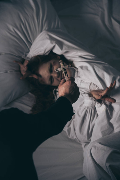 esorcista tenendo croce sopra demone femminile a letto
 - Foto, immagini