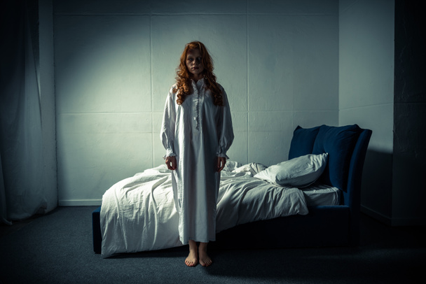 ανατριχιαστικό δαιμονικό κορίτσι με νυχτικό στέκεται στην κρεβατοκάμαρα - Φωτογραφία, εικόνα