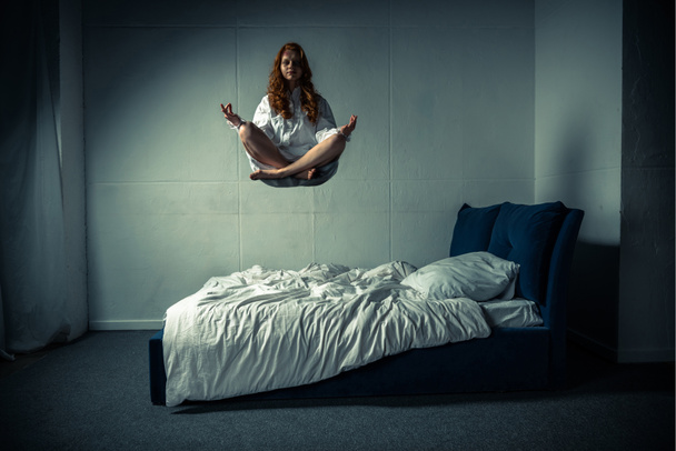 obsessed girl levitating in lotus pose during meditation over bed - Foto, Imagen