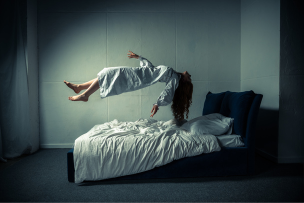 donna raccapricciante in camicia da notte dormire e levitare sul letto
 - Foto, immagini