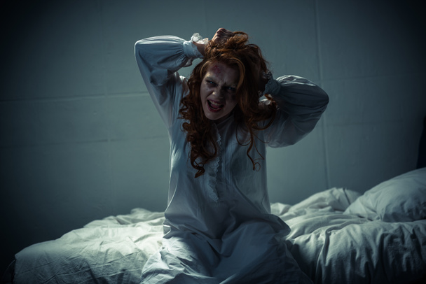 creepy girl in nightgown screaming in bedroom - Foto, afbeelding