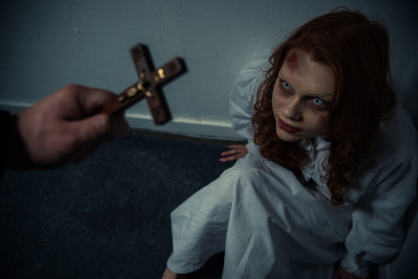 exorcista sosteniendo cruz delante de chica obsesionada
 - Foto, imagen