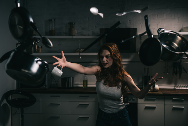 hátborzongató démoni lány lebegő edényekkel és késekkel a konyhában - Fotó, kép