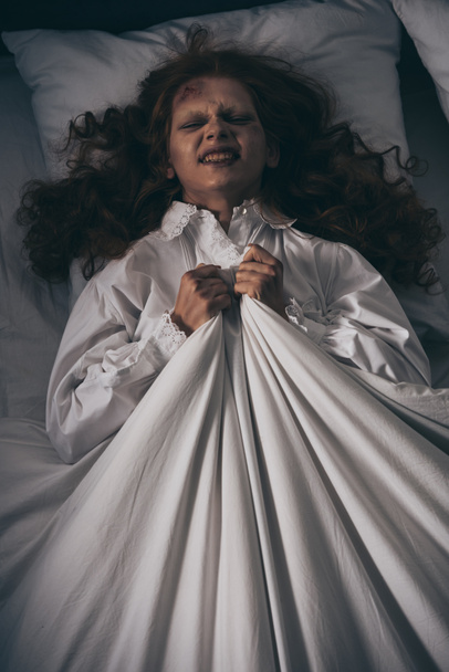 vrchní pohled na démonické ženy v noční košili ležící v posteli - Fotografie, Obrázek