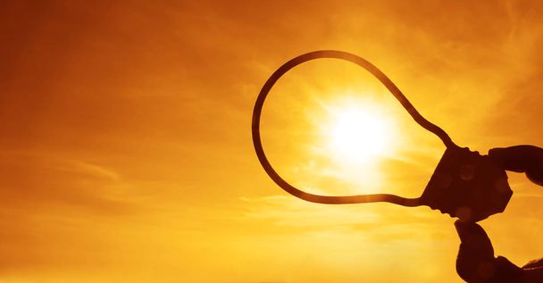 male hand hold bubble, bulb sign on sunny sunset sky background. sun rays.  - Photo, image