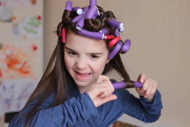 Красива весела дівчина восьми років крутить бігунів на довге волосся
 - Фото, зображення