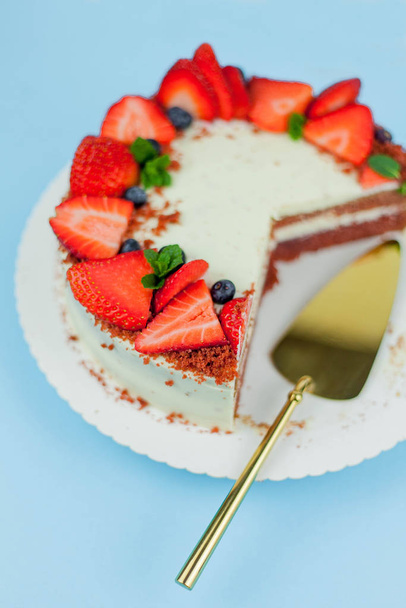 Bella torta con bacche con crema di burro su sfondo blu. Torta con torte rosse
. - Foto, immagini