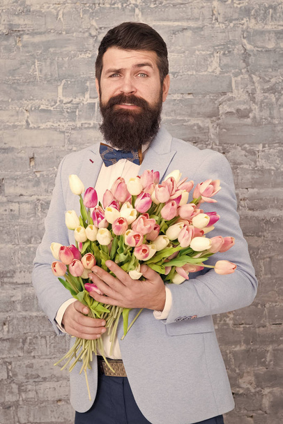 How to be gentleman. Guide for modern man. Romantic man with flowers. Romantic gift. Macho getting ready romantic date. Tulips for sweetheart. Man well groomed tuxedo bow tie hold flowers bouquet - Photo, image
