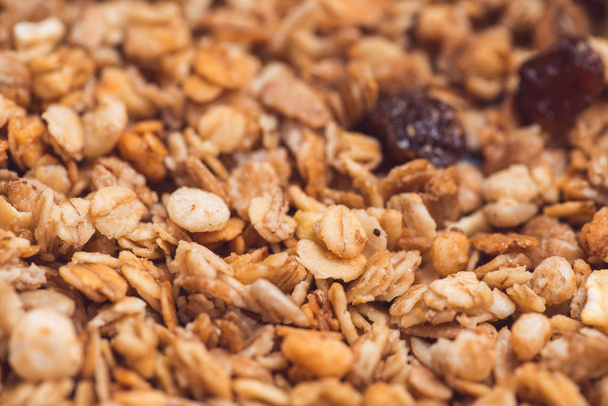 Useful and tasty muesli with nuts, rasins and flakes. Selective focus macro shot with very shallow depth of field. Healthy and vegetarian lifestyle - Φωτογραφία, εικόνα