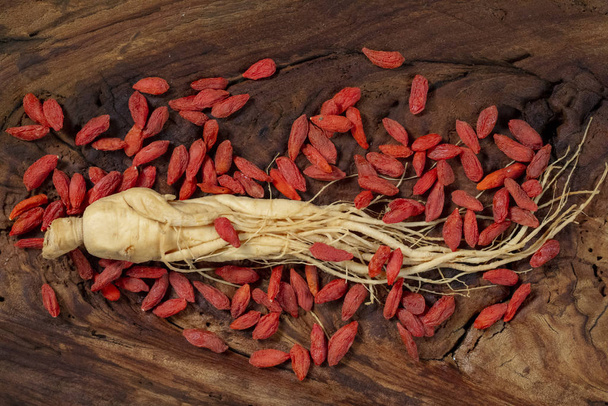Ginseng e wolfberry sulla tavola di legno originale, materiale medicinale comune in Asia
 - Foto, immagini