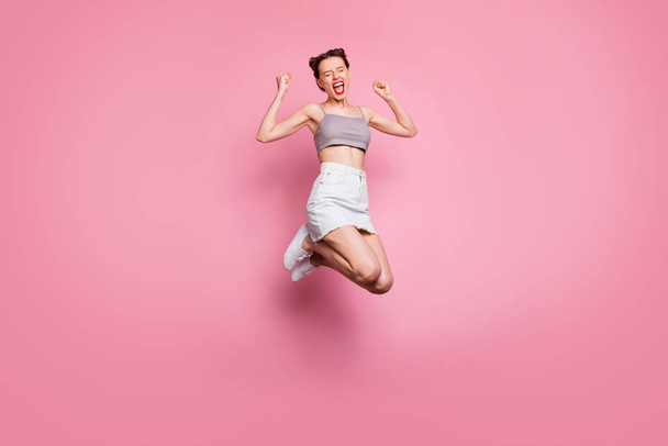 Full body photo of delighted positive girl jump win lottery have discounts news scream yeah yes raise fists feel rejoice emotions wear casual style clothes isolated pink color background - 写真・画像