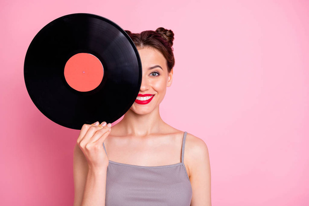 Portrait of positive cheerful girl hide her face with circle turntable vinyl disc want listen retro music hits wear good look clothes isolated over pastel color background - Foto, Imagem