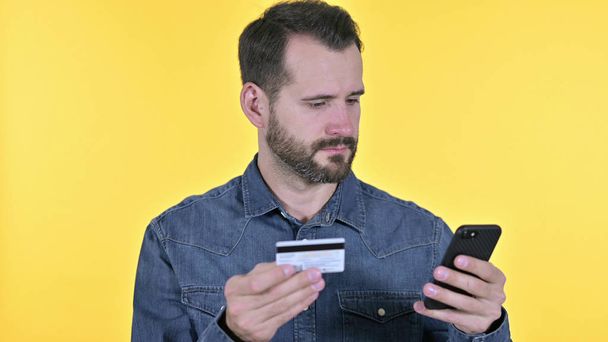 Online maksu älypuhelimella nuoren miehen, Keltainen tausta
 - Valokuva, kuva