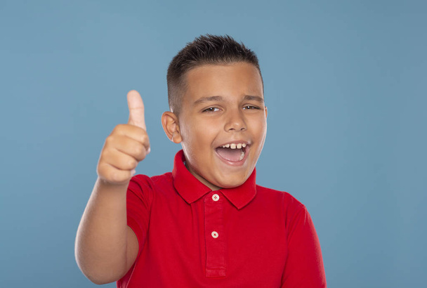 Молодий хлопчик сміється дає тобі схвальний жест проти Блю
 - Фото, зображення