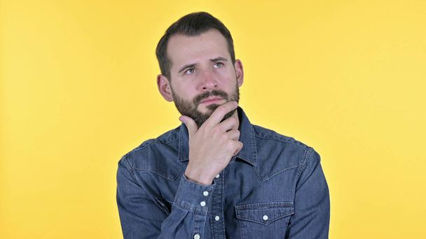 Porträt eines jungen Mannes, der über Idee nachdenkt, gelber Hintergrund - Foto, Bild