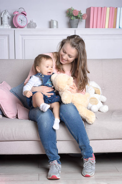 Äiti ja tytär istuvat sohvalla lelun kanssa
 - Valokuva, kuva