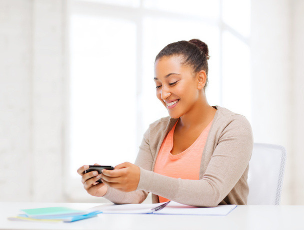 African woman with smartphone in office - Foto, Bild