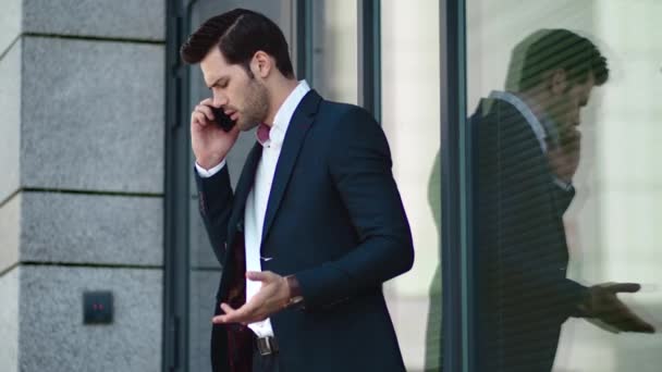 Closeup man arguing by phone at street. Businessman talking phone near building - Záběry, video
