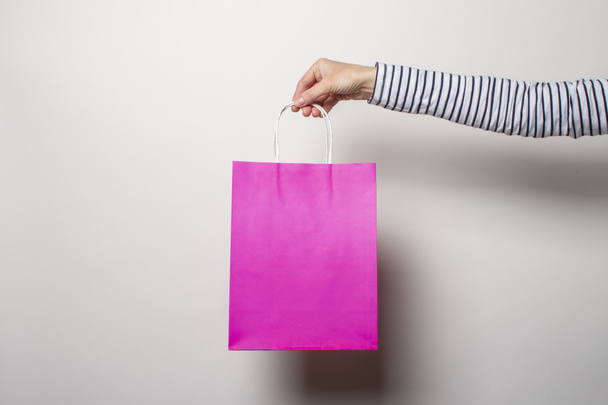 Main féminine tient un sac à provisions sur un fond blanc. Concept shopping, remise, vente. Bannière
 - Photo, image
