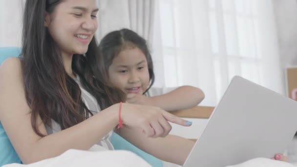 Asian girls and sisters are using laptops, computers and tablets to connect to the cyber world. The little girl rested at home using the internet. - Imágenes, Vídeo