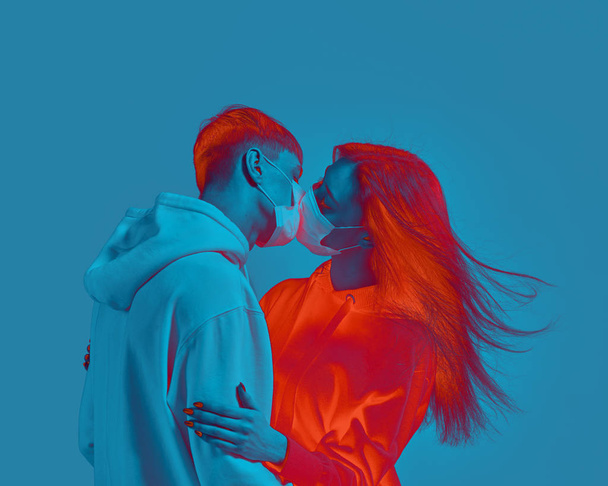 Boy and girl kiss. Medical protective mask on face. Fear of virus infection. Modern poster design with copy space. - Foto, imagen