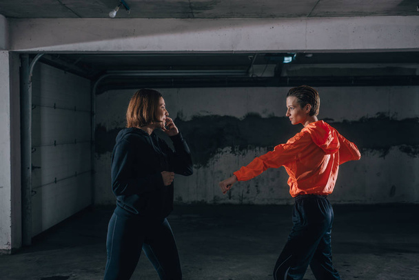 Zwei Sportlerinnen zeigen technisches Geschick beim Kämpfen in einer Garage - Foto, Bild