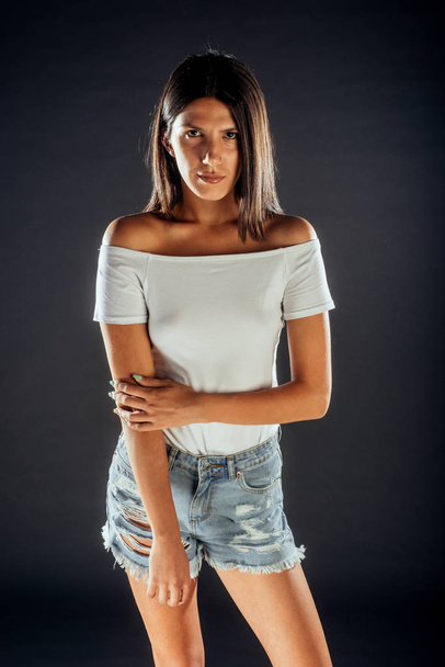 Trendy modern woman wearing ripped denim shorts and white top - Photo, Image