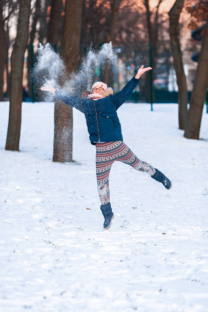 Happy teenage girl throwing snowballs and jumping - Foto, Imagen