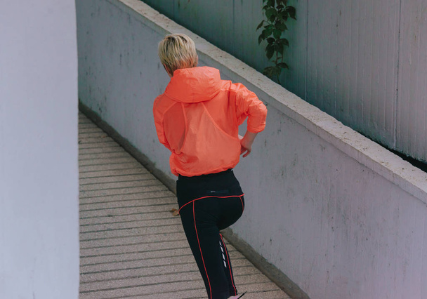 Junge gesunde Läuferin während eines urbanen Workouts - Foto, Bild