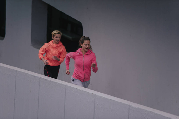 Duas atletas atraentes se preparando para uma corrida em um ambiente urbano
 - Foto, Imagem