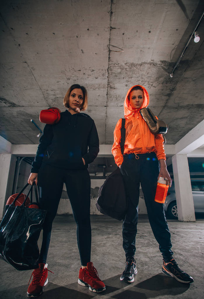 Two female boxer friends standing in a garage with boxing equipment - Foto, imagen