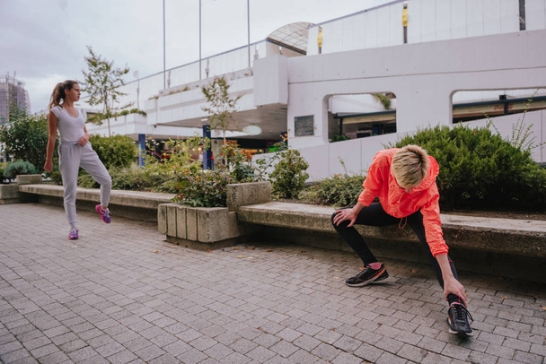 Attraktive Sportlerinnen beim Stretching in einer städtischen Umgebung - Foto, Bild
