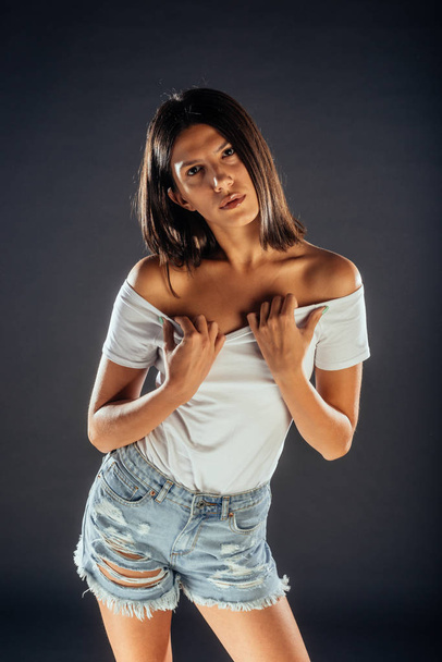 Studio shot of a stylish fashion girl posing against dark background - Photo, Image