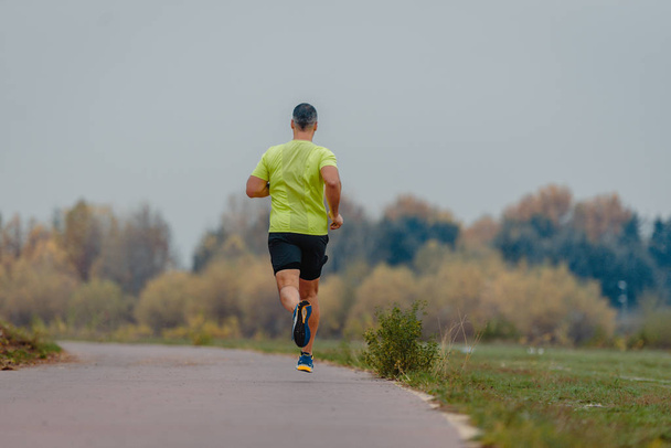 Muskulöser älterer Mann über 40 in Sportbekleidung, der im Freien läuft - Foto, Bild