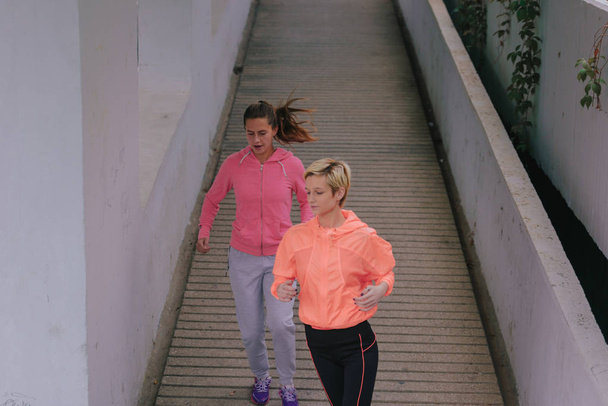 Nuoret terveet naisjuoksijat urbaanin harjoittelun aikana
 - Valokuva, kuva