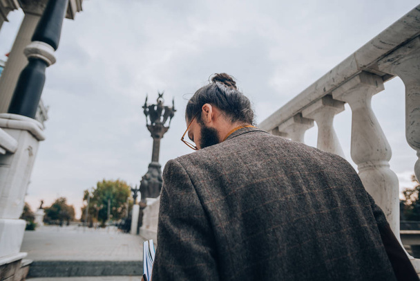 Moderno giovane uomo d'affari con i capelli lunghi e la barba al lungomare della città
 - Foto, immagini