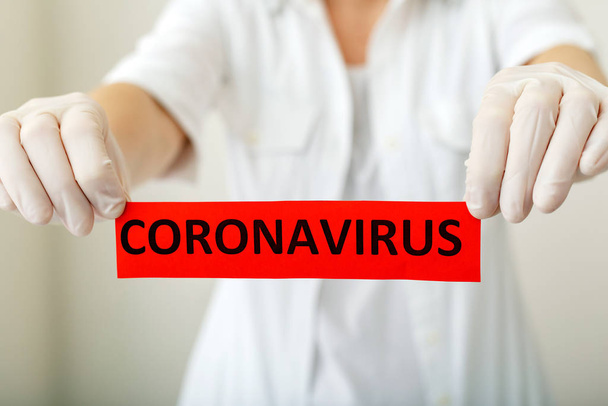 Coronavirus, red warning sign with the text Coronavirus in doctor hands in white coat and gloves. Epidemic, Chinese coronavirus 2020, Wuhan virus, Chinese Coronavirus outbreak influenza. - Fotografie, Obrázek
