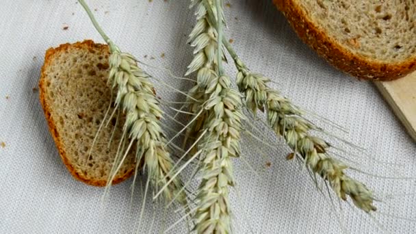 Нарезанный хлеб цельное зерно на столе со скатертью, уши лежат рядом, здоровое питание, день здоровья
 - Кадры, видео