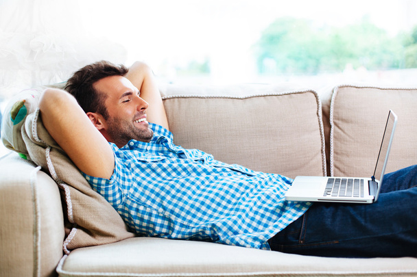 Man relaxing with laptop on couch - Fotó, kép