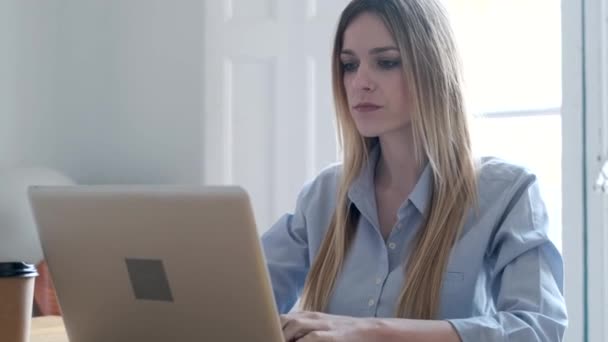 Vídeo de mulher de negócios jovem concentrada trabalhando com laptop na mesa no escritório
. - Filmagem, Vídeo