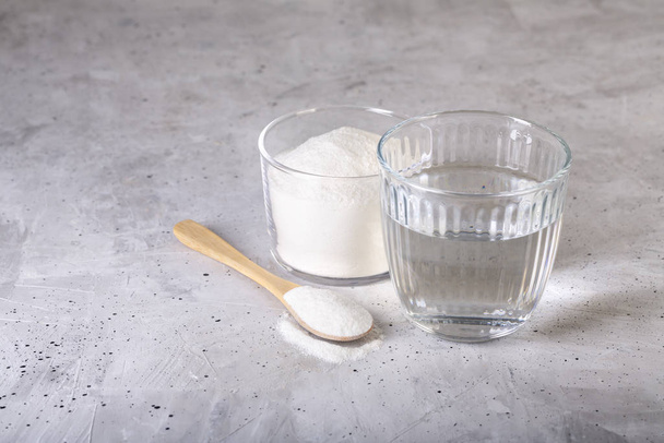 Collagen protein powder - Hydrolyzed. Spoon and glass of water. - Foto, Bild