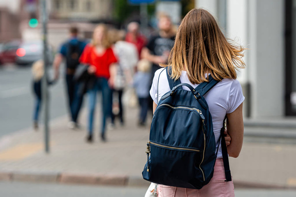Vista posterior de la joven con mochila sobre un fondo borroso de la calle
 - Foto, Imagen