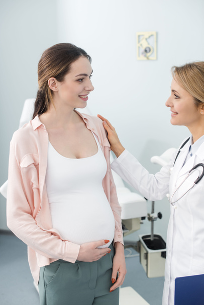 mosolygó terhes nő konzultált orvossal a nőgyógyászati klinikán - Fotó, kép