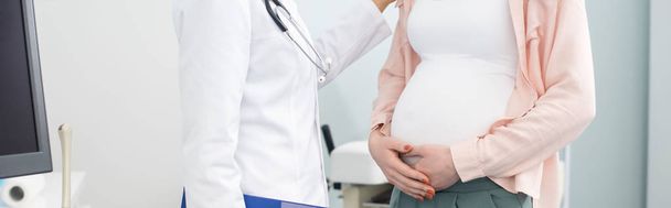 panoramisch shot van zwangere vrouw na overleg met arts in gynaecologische kliniek - Foto, afbeelding