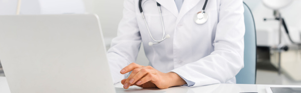 panoramiczne ujęcie profesjonalnej lekarki pracującej na laptopie w klinice   - Zdjęcie, obraz