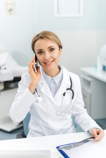 médecin souriant tenant échographie et parler sur smartphone à la clinique
  - Photo, image