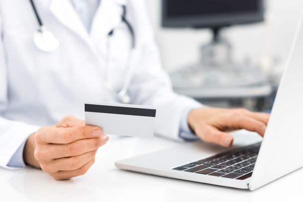 przycięty widok lekarza za pomocą laptopa i karty kredytowej w klinice - Zdjęcie, obraz